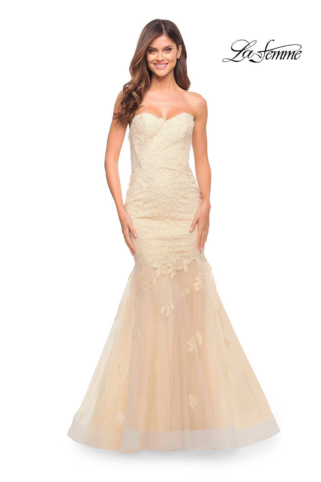 A woman models the Sheer-Back La Femme Strapless Mermaid Prom Dress, a fitted, cream lace gown with a corset back, set against a white background featuring the